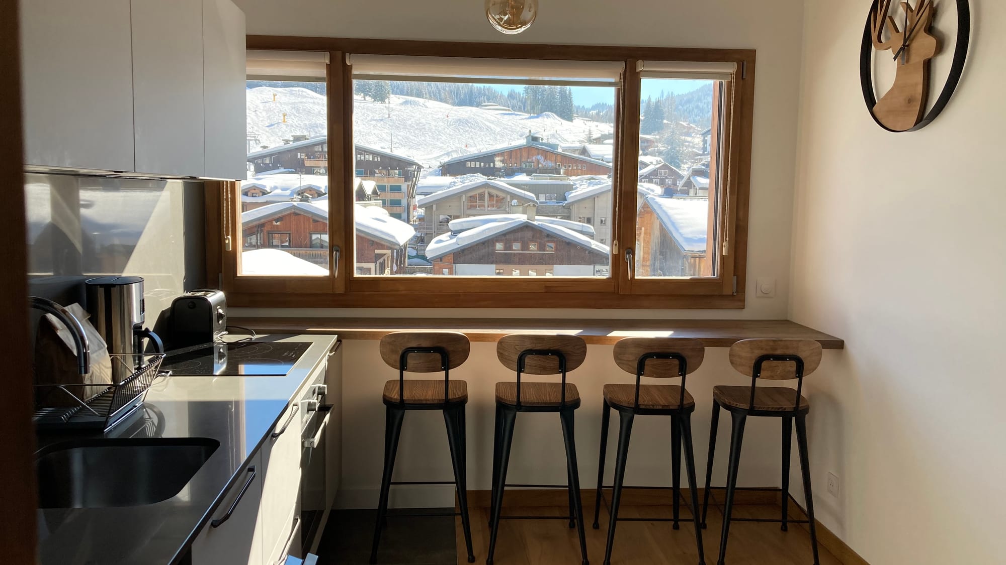 Open-kitchen with view on snowy village and ski slopes